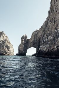 Rock formations by sea against clear sky