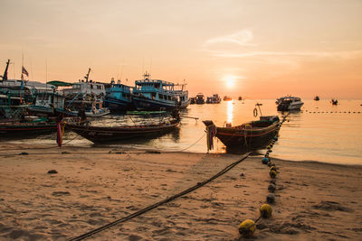 Boats moored at harbor against sky during sunset