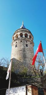 Low angle view of flags against clear blue sky