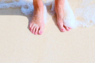 Low section of woman on wet sand at beach