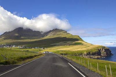 Road amidst green landscape against sky