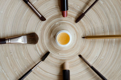 Natural vegan makeup on a wooden background - mascara, brushes, lipstick, gloss, pencil.