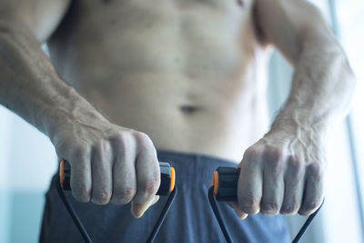 Midsection of shirtless man exercising in gym