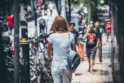 Rear view of women walking on street in city