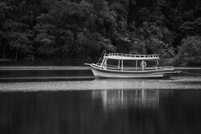 Boat moored in lake against trees in forest