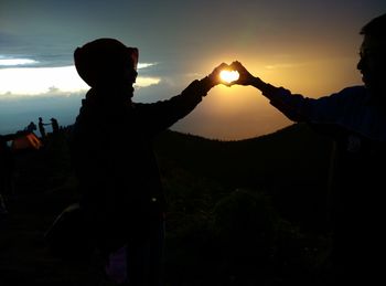 Silhouette couple standing against sky during sunset