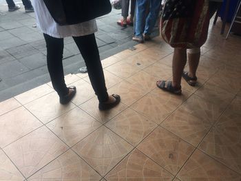 Low section of people walking on tiled floor