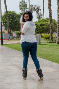 Full length portrait of young woman wearing inline skating while standing at park