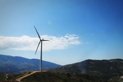 Windmills by mountains against sky