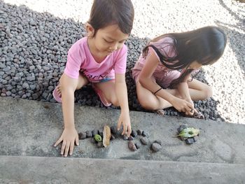 High angle view of cute kids playing with stones outdoors
