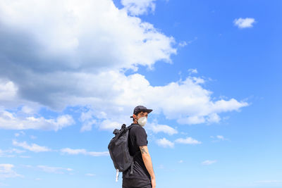 Low angle view of man standing against blue sky