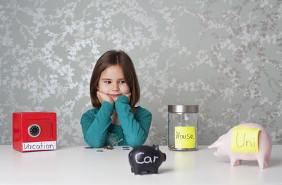 Portrait of girl on table against wall