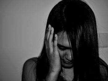 Close-up of woman covering ear against wall