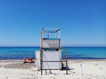 Lifeguard hut on beach against clear blue sky