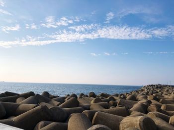 Tetrapods at beach against blue sky