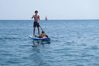 A young sports man with a child sails on a sup in the sea. healthy lifestyle concept