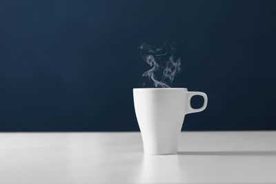 Close-up of coffee cup on table against blue background