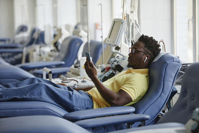 Man donating blood and using smart phone