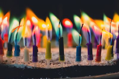 Close-up of colorful candles burning on birthday cake