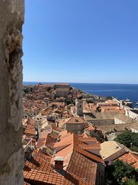 Aerial view of townscape by sea against clear blue sky