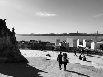 People by sea against sky in city