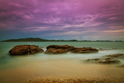 Rocks on shore against sky during sunset