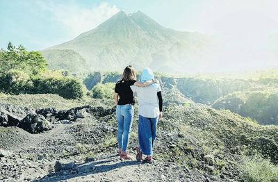 Friends standing on mountain against sky