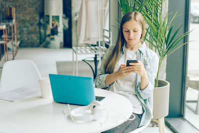 Young woman using mobile phone on table