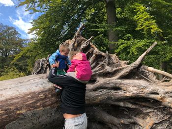 Father with son and daughter against tree trunk