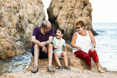 Full length of grandparents and grandson at beach