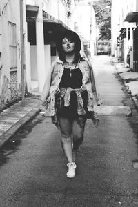 Full length portrait of young woman walking on road