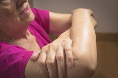 Close-up midsection of senior woman with arms crossed at home