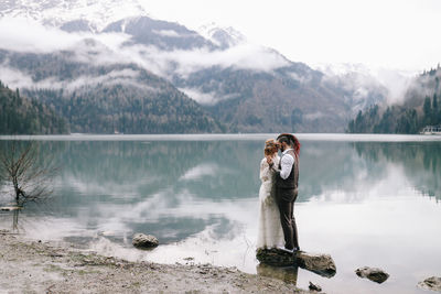 A happy couple in love and married embrace in nature by the lake and the misty mountains