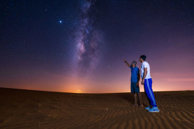 Man and woman standing against clear sky at night