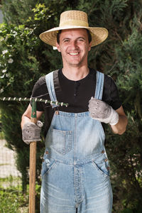 Portrait of smiling farmer with rake while standing outdoors