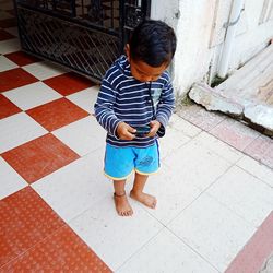 High angle view of boy standing on tiled floor