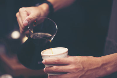 Close-up of hand pouring drink in glass