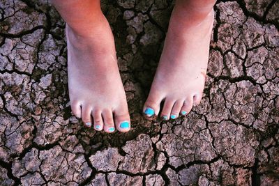 Low section of girl standing on cracked field