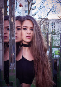 Portrait of beautiful female model standing by wall with reflection