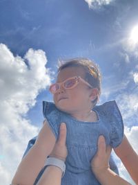 Low angle view of young woman standing against sky