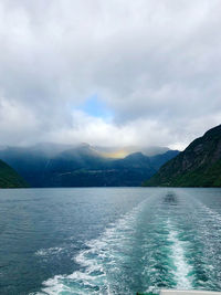 Scenic view of sea by mountains against sky