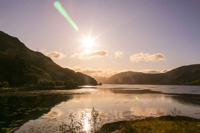 Scenic view of lake and mountains against sky at sunset