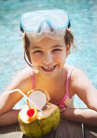 Smiling girl having coconut water at poolside