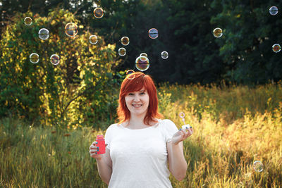 Portrait of young woman standing against plants