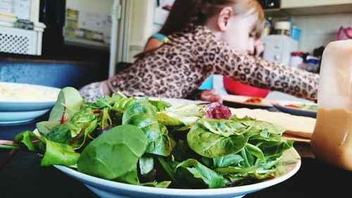 Close-up of salad in bowl with girl in background