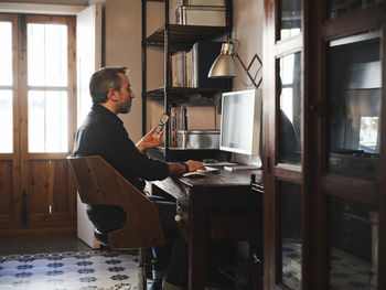 Side view of man sitting at home