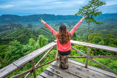 Rear view of woman with arms outstretched on mountain