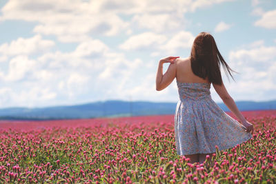 Rear view of woman with red flowers on field