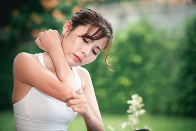 Young woman looking away while standing outdoors