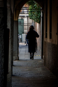 Rear view of woman walking in corridor of building